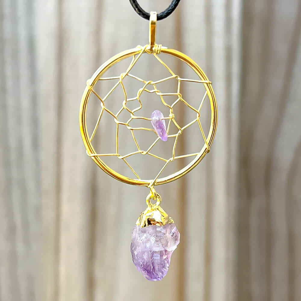 Gorgeous gold plated Amethyst Dreamcatcher gold Necklace adorned with an Amethyst crystal bead and a raw Amethyst crystal hanging from the bottom. Shop at Magic Crystals for Amethyst Jewelry, Healing Crystals, and Stones. Perfect gift for someone or to wear every day. Boho Jewelry, February Birthstone.